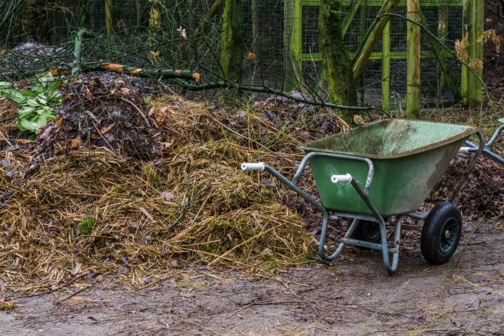 wheelbarrow next to a compost pile