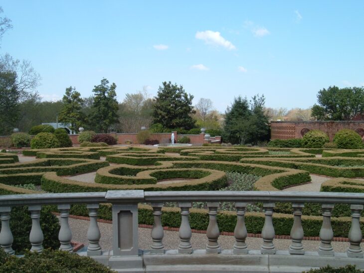 Low clipped boxwood hedges forming a patterned parterre behind a stone balustrade